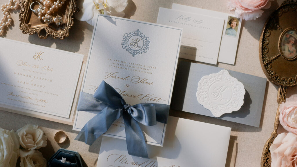 Flatlay detail shot of blue and white invitation suite with bridal heirlooms