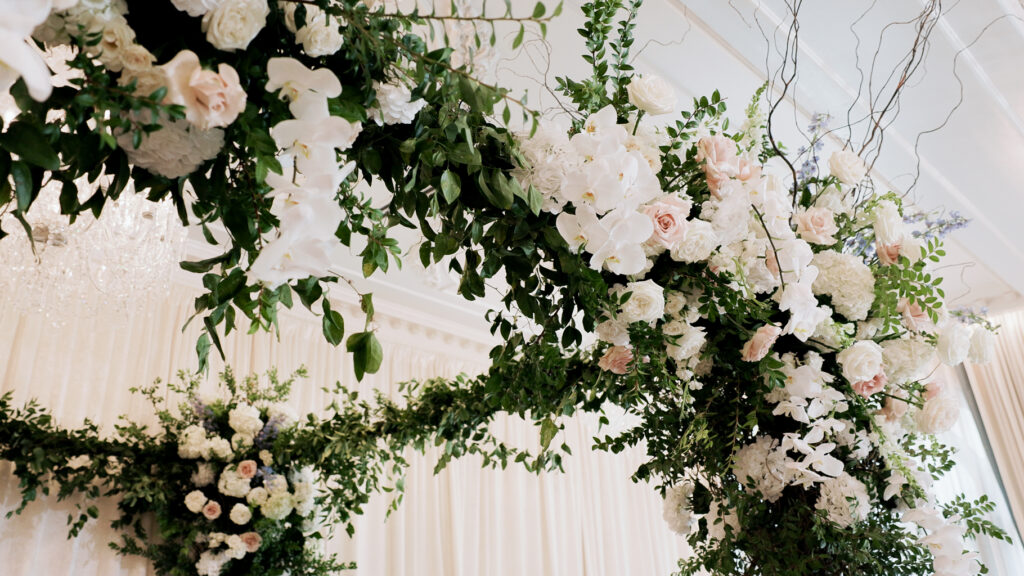 White and pink floral covered chuppah with greenery 